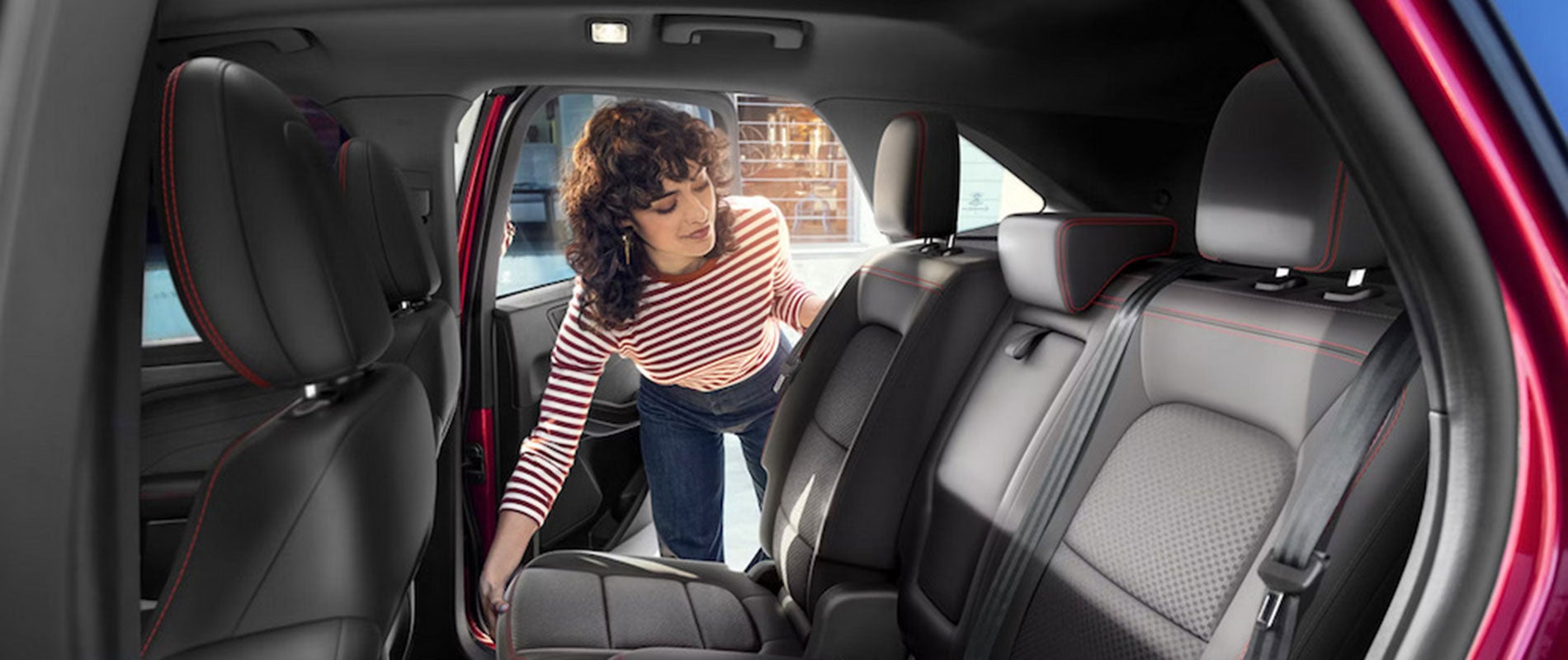 A woman adjusting the back seat of a red 2026 Ford Escape