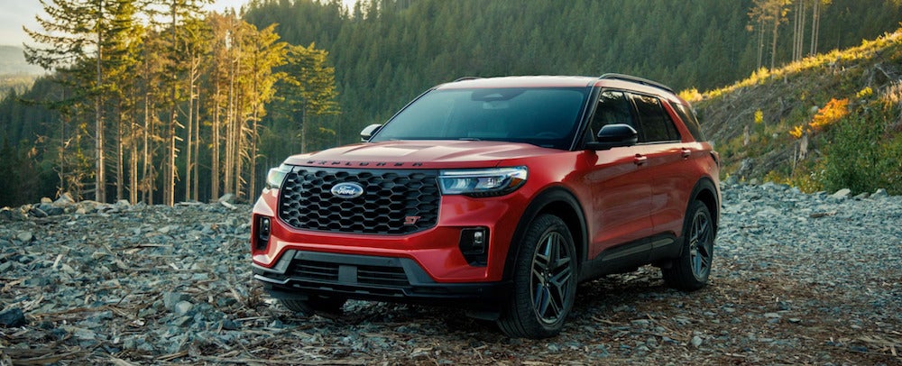 A red 2026 Ford Explorer SUV parked on a rocky ledge with trees in the background